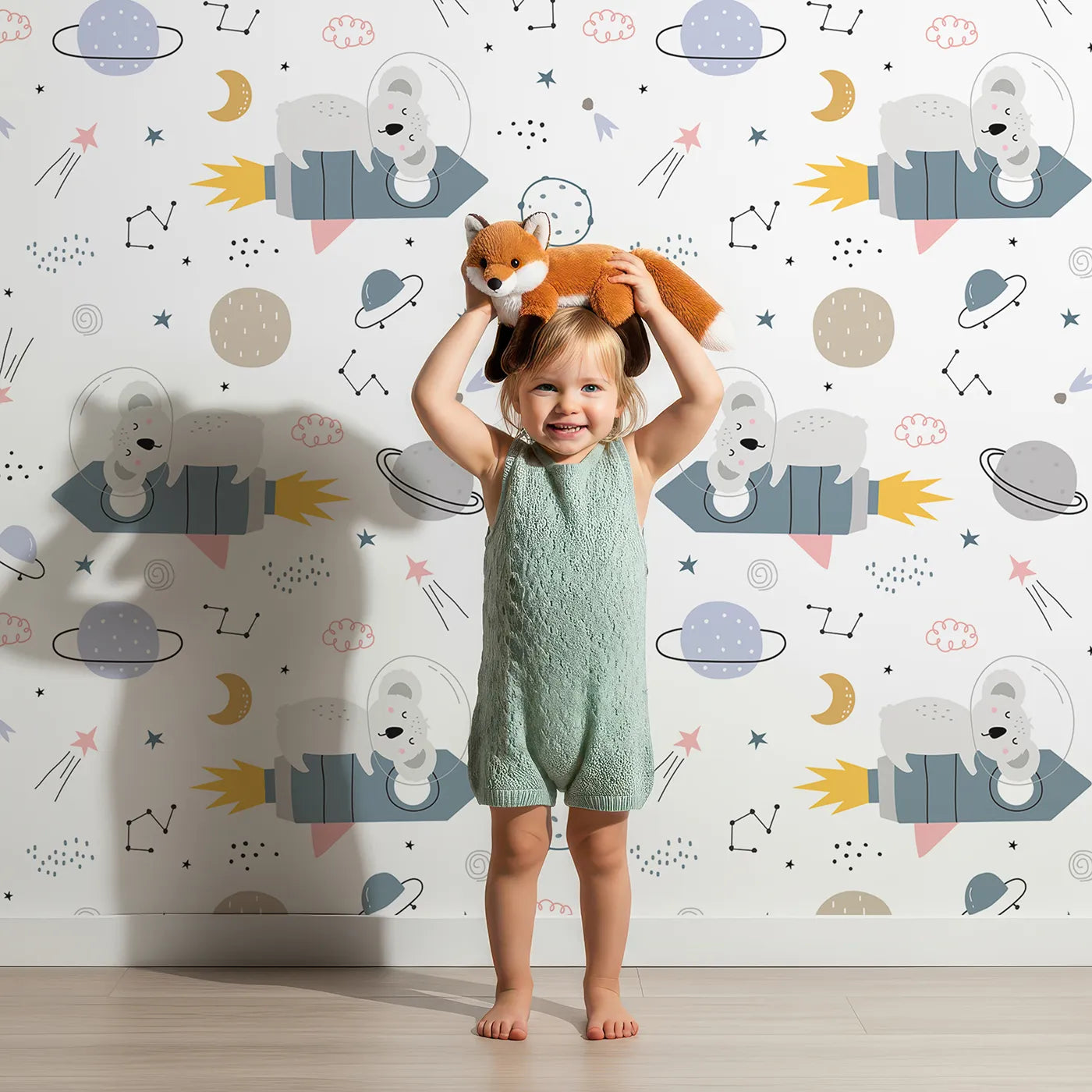 Lovely child standing in front of Whimsy Tots Koala Rocket Ride Wallpaper with koala, space, rocket, planet, star in design.
