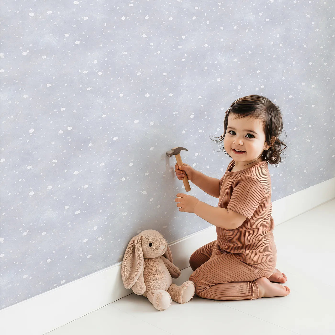 Lovely child standing in front of Whimsy Tots First Snowfall Wallpaper in Gray with snow, winter, gray, abstract, texture in design.
