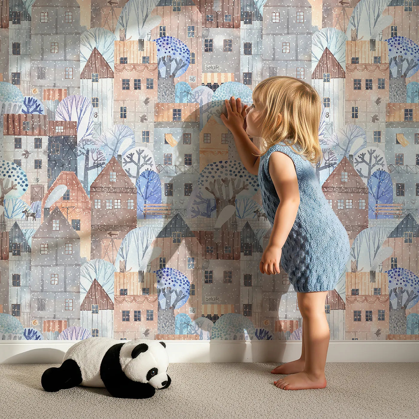 Lovely child standing in front of Whimsy Tots Snowy Watercolor Village Wallpaper with city, snow, winter, house, watercolor in design.