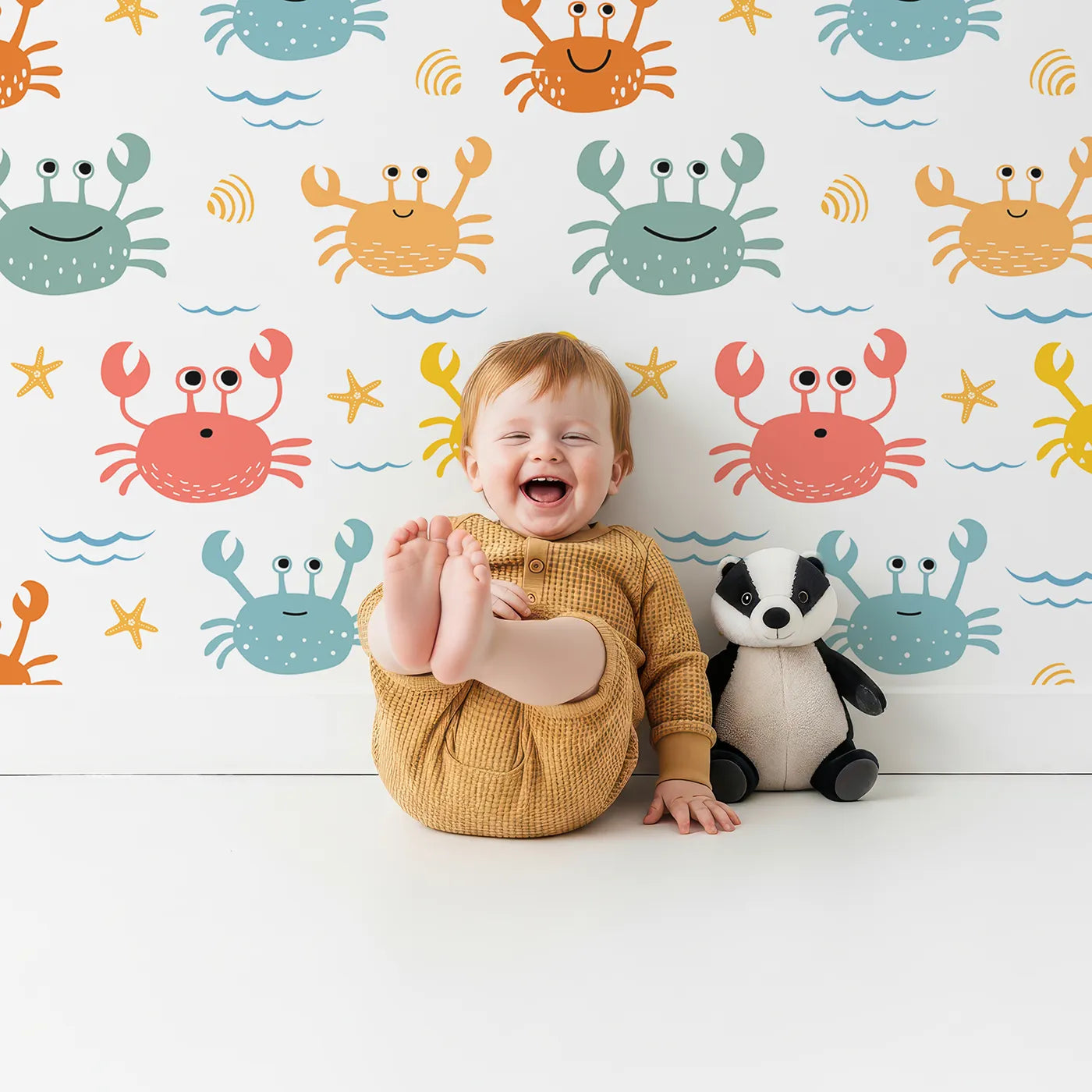 Lovely child standing in front of Whimsy Tots Happy Crab Friends Wallpaper with crab, sea, ocean, beach, cute in design.