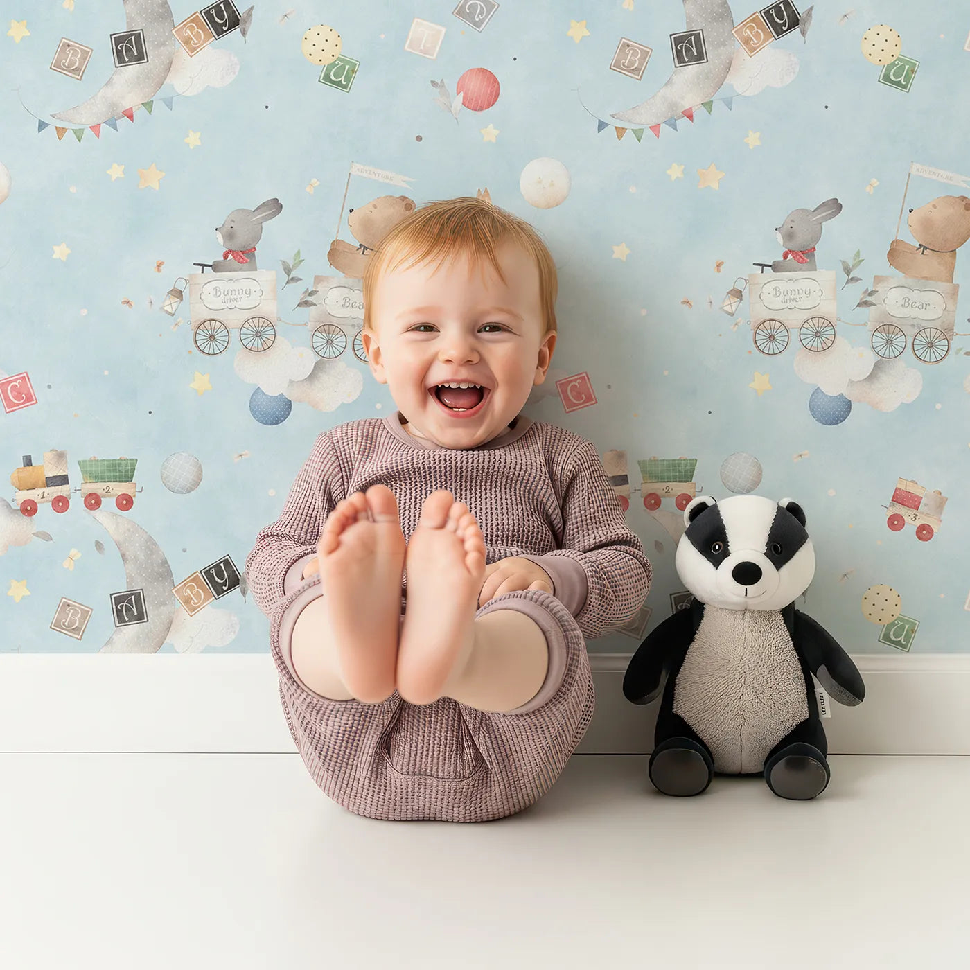 Lovely child standing in front of Whimsy Tots Storybook Sky Train Adventure Wallpaper with train, sky, animal, moon, watercolor in design.