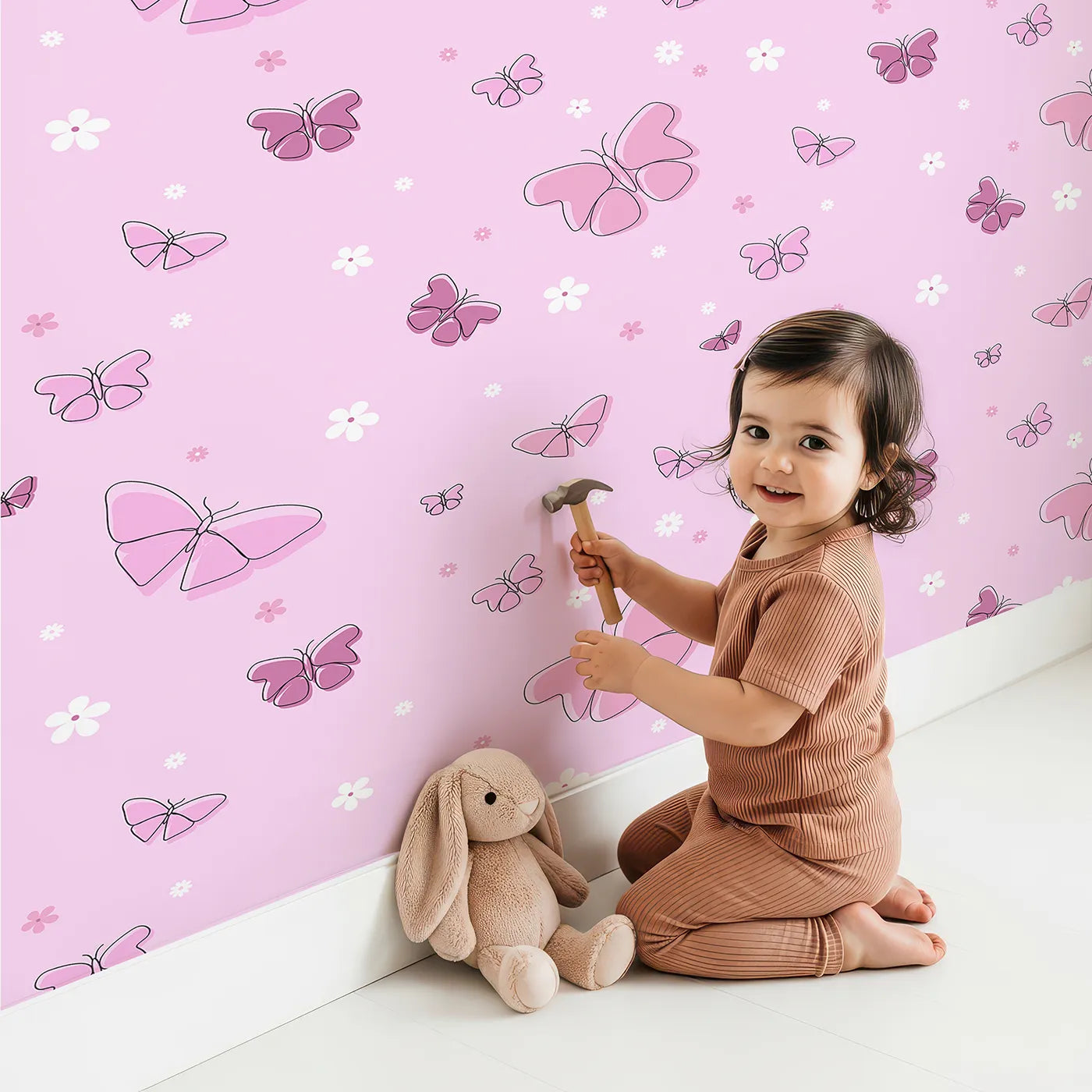 Lovely child standing in front of Whimsy Tots Minimalist Butterfly Garden Wallpaper in Pink with butterfly, flower, minimalist, pink, line art in design.