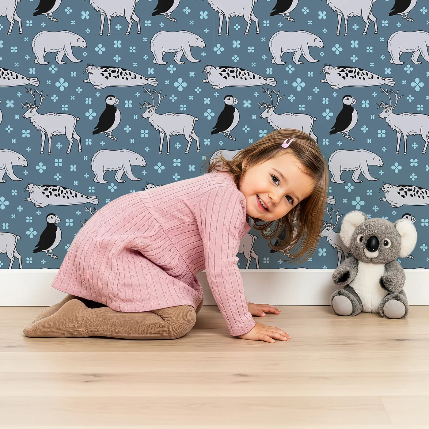 Lovely child standing in front of Whimsy Tots Arctic Animal Friends Wallpaper with arctic, polar bear, reindeer, seal, puffin in design.