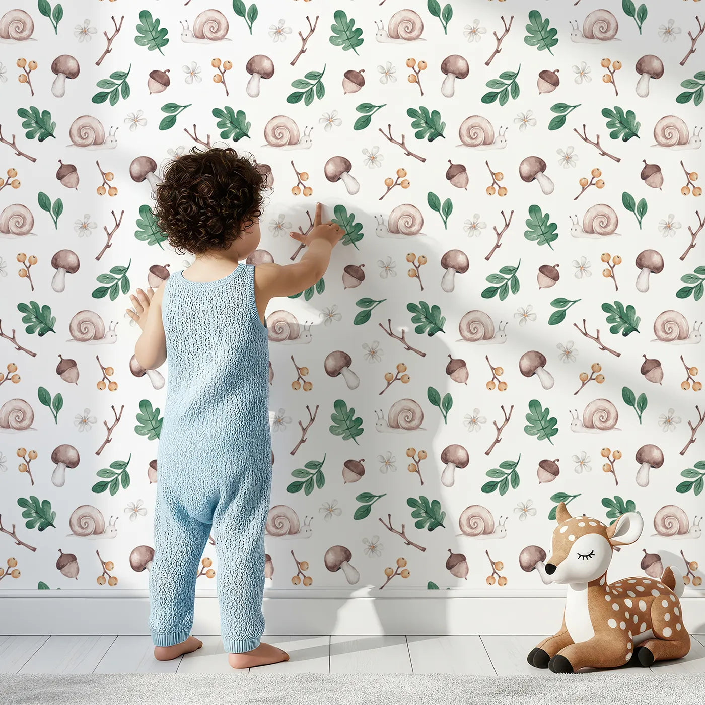 Lovely child standing in front of Whimsy Tots Watercolor Woodland Treasures Wallpaper with snail, mushroom, acorn, watercolor, woodland in design.