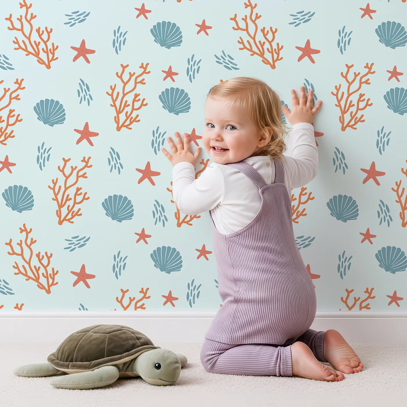Lovely child standing in front of Whimsy Tots Coastal Coral Garden Wallpaper with coral, starfish, shell, sea, ocean in design.