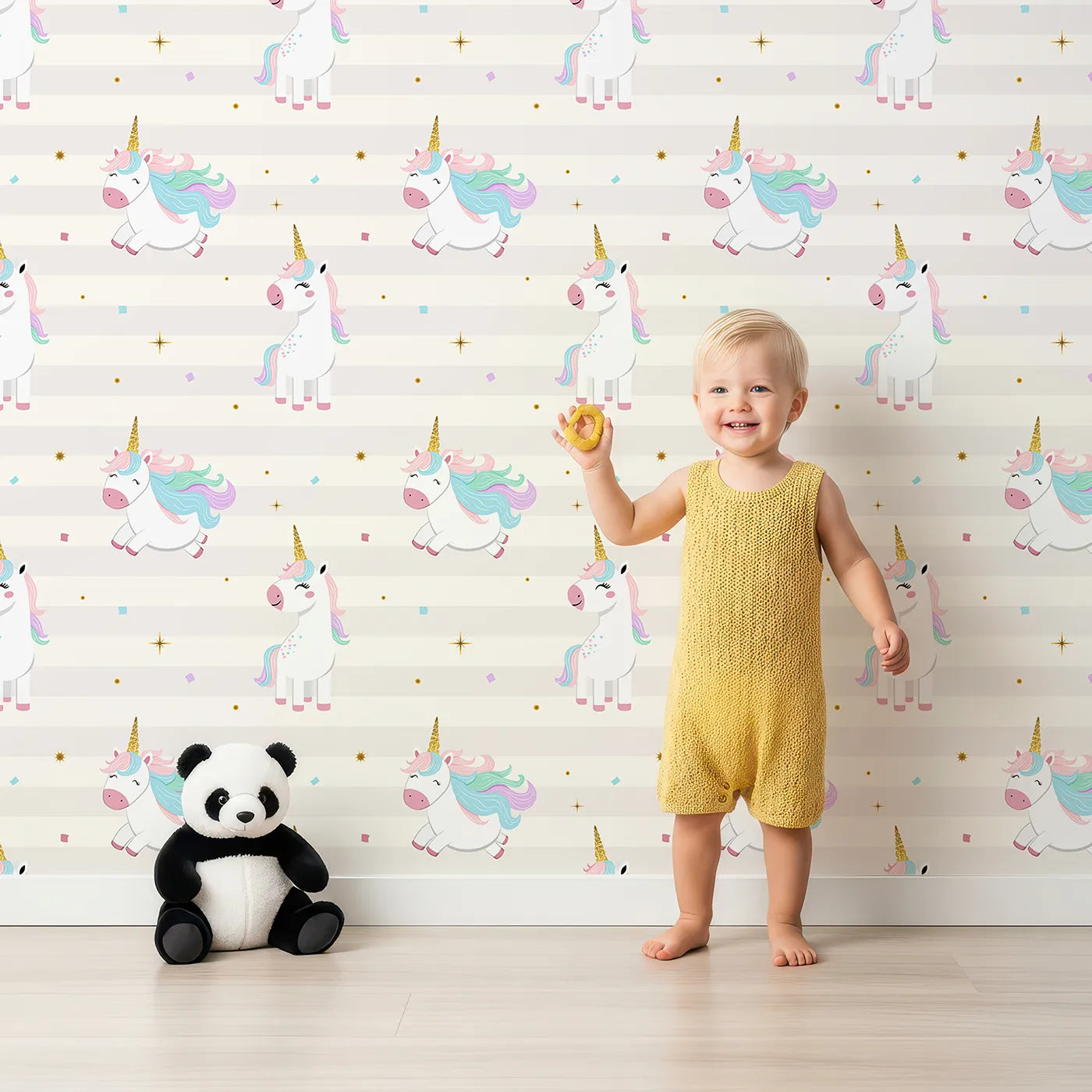 Lovely child standing in front of Whimsy Tots Flying Unicorn Party Wallpaper with unicorn, flying, glitter, stripe, rainbow in design.
