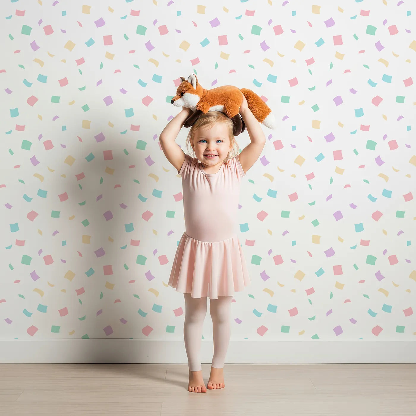 Lovely child standing in front of Whimsy Tots Pastel Confetti Celebration Wallpaper with confetti, pastel, rainbow, dot, geometric in design.
