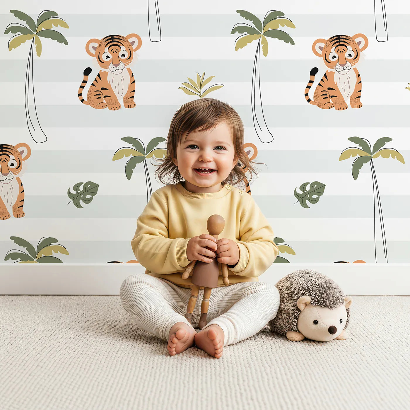 Lovely child standing in front of Whimsy Tots Striped Tiger Jungle Wallpaper with tiger, palm tree, tropical, jungle, stripe in design.