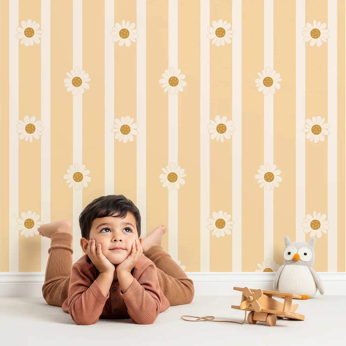 Lovely child standing in front of Whimsy Tots Daisy Lane Stripe Wallpaper in Yellow with daisy, flower, stripe in design.
