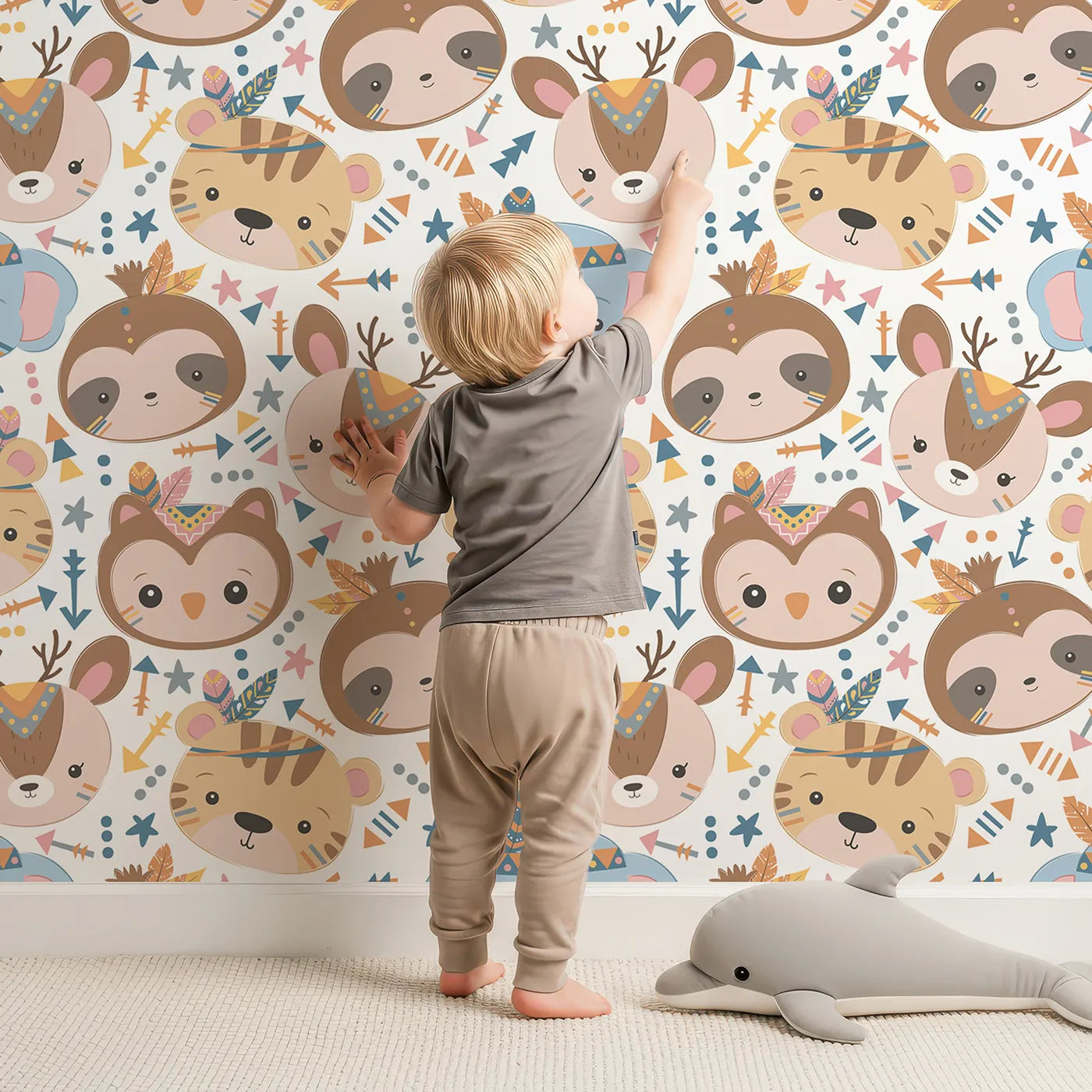 Lovely child standing in front of Whimsy Tots Wild Whimsy Tribe Wallpaper with bear, deer, elephant, tiger, owl, sloth, arrow, feather, star in design.