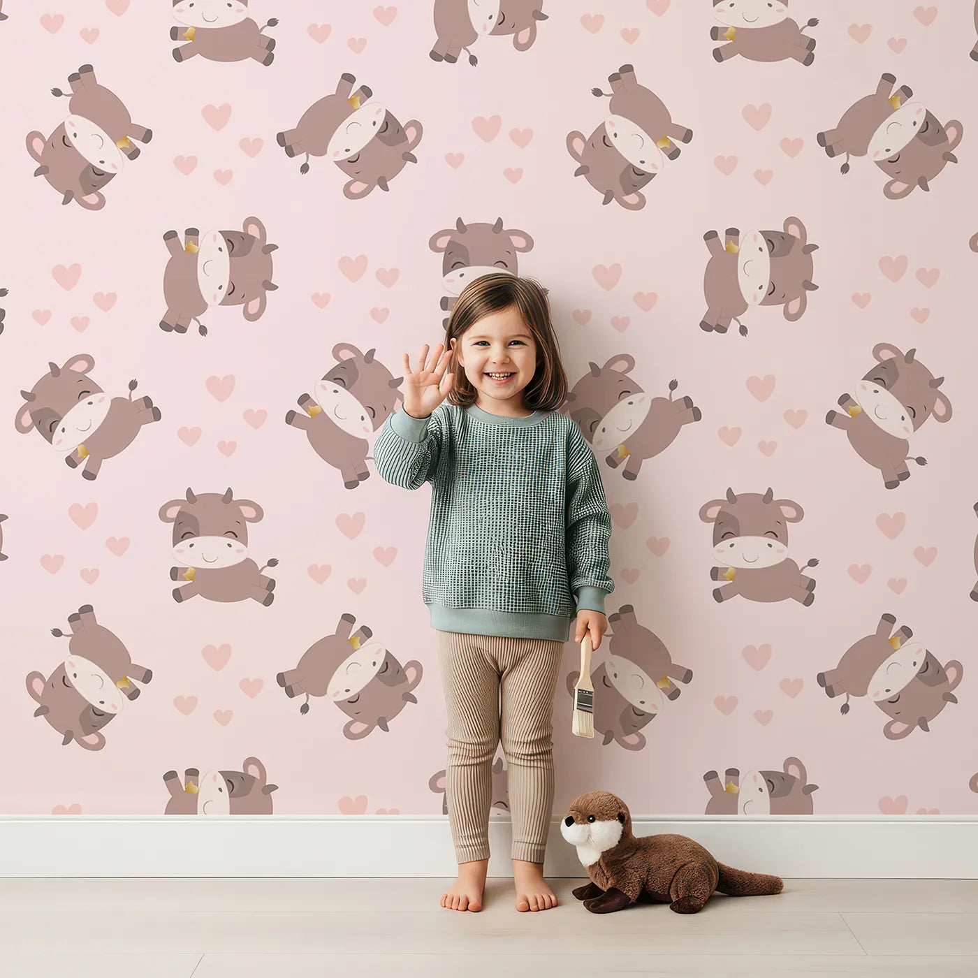 Lovely child standing in front of Whimsy Tots Moo Moo Love Wallpaper in Pink with cow, heart, bell in design.