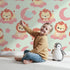 Lovely child standing in front of Whimsy Tots Starry Safari Dreams Wallpaper in Mint Green with lion, cloud, moon, star in design.
