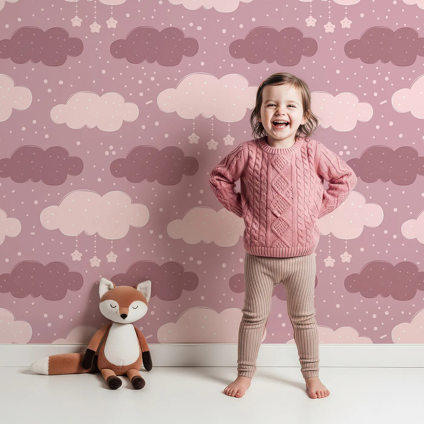 Lovely child standing in front of Whimsy Tots Dreamy Drizzle Clouds Wallpaper in Pink with cloud, star, sprinkle in design.