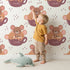 Lovely child standing in front of Whimsy Tots Lovely Tea Mice Wallpaper in White with mouse, cup, sprinkle in design.