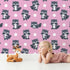 Lovely child standing in front of Whimsy Tots Playful Raccoon Parade Wallpaper in Pink with raccoon, dot in design.