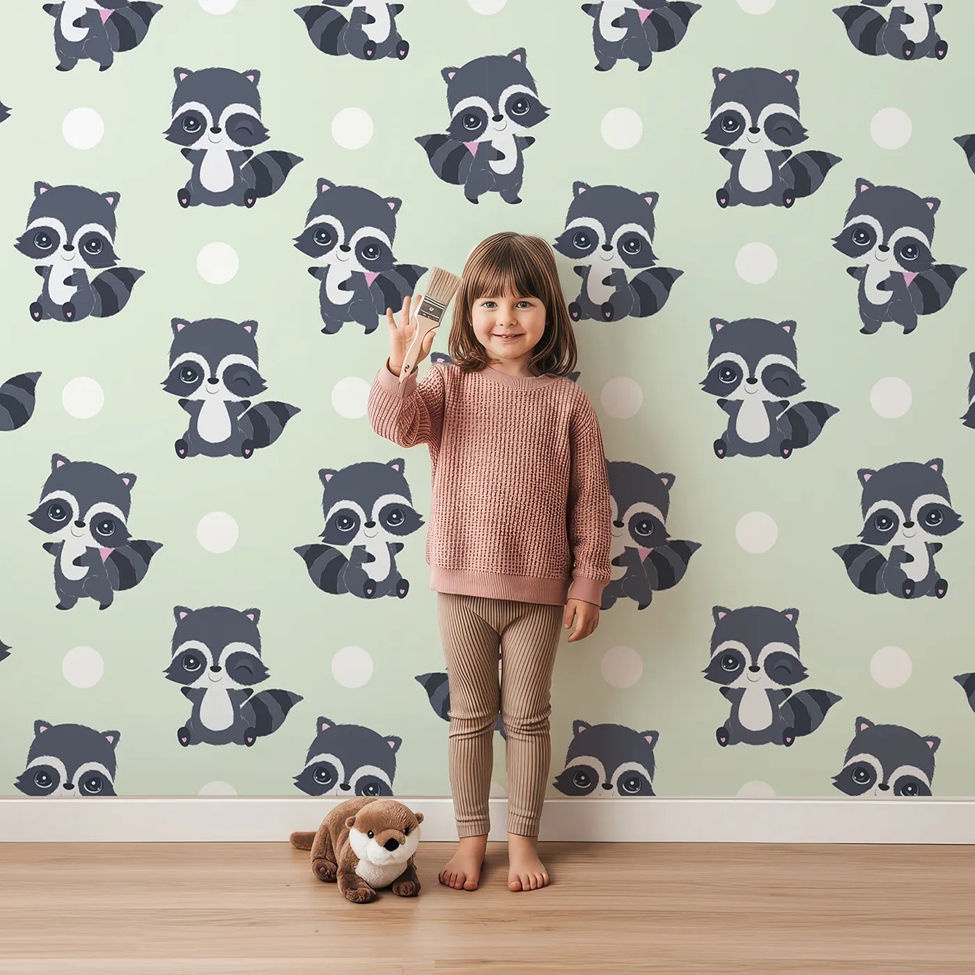 Lovely child standing in front of Whimsy Tots Playful Raccoon Parade Wallpaper in Green with raccoon, dot in design.
