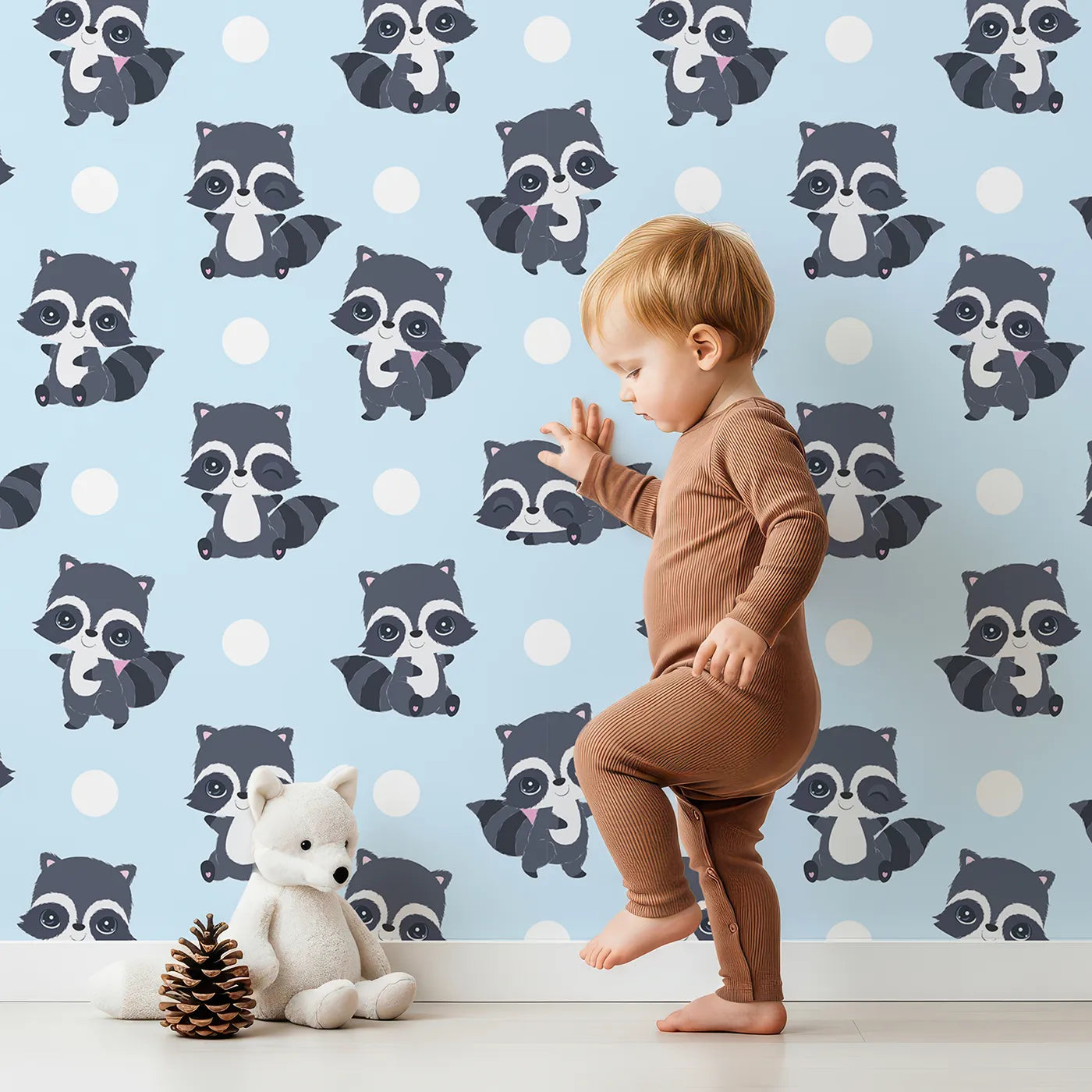 Lovely child standing in front of Whimsy Tots Playful Raccoon Parade Wallpaper in Blue with raccoon, dot in design.
