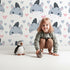 Lovely child standing in front of Whimsy Tots Zebra Snuggle Smiles Wallpaper in Pink with zebra, heart, face in design.