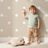 Lovely child standing in front of Whimsy Tots Polka Dot Whimsy Wallpaper in Beige with dot, polka in design.