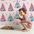 Lovely child standing in front of Whimsy Tots Tribal Camp Panda Wallpaper in Pink with panda, teepee, feather, arrow, dot in design.