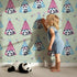 Lovely child standing in front of Whimsy Tots Tribal Camp Panda Wallpaper in Sage Green with panda, teepee, feather, arrow, dot in design.