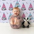 Lovely child standing in front of Whimsy Tots Tribal Camp Panda Wallpaper in Lavender with panda, teepee, feather, arrow, dot in design.