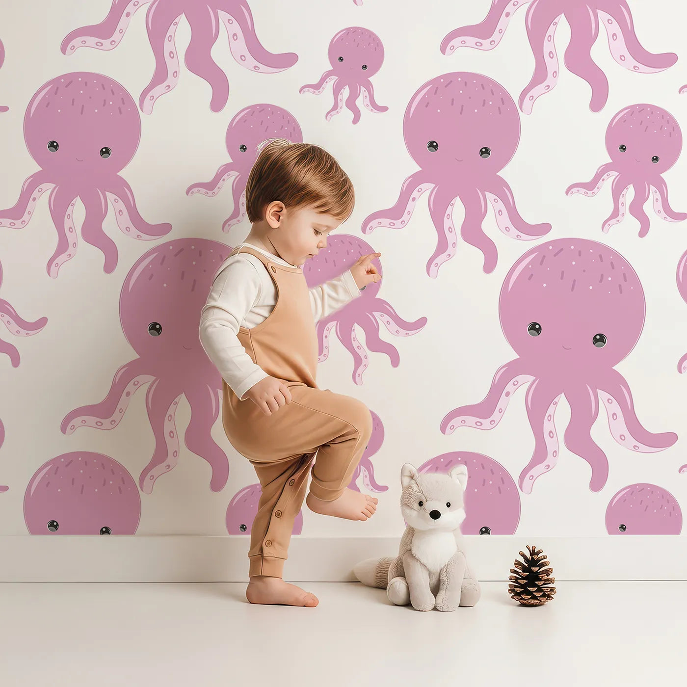 Lovely child standing in front of Whimsy Tots Ocean Bubbles Octopus Wallpaper in Pink with octopus, tentacle, dot, sea in design.