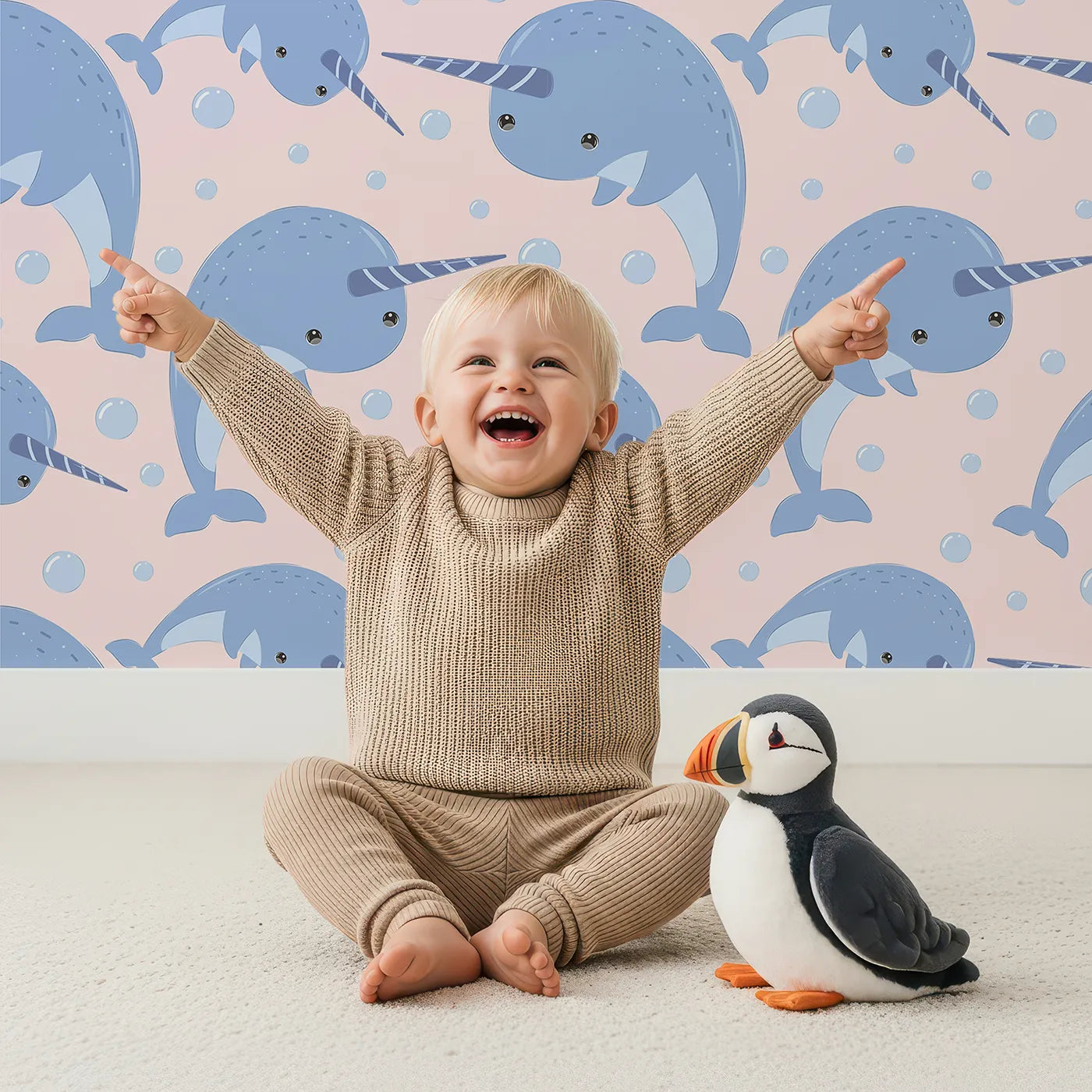 Lovely child standing in front of Whimsy Tots Bubbly Narwhal Parade Wallpaper in Blue with narwhal, horn, bubble, sea in design.