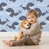 Lovely child standing in front of Whimsy Tots Orca Whale Wonder Wallpaper in Blue with whale, orca, bubble, wave in design.