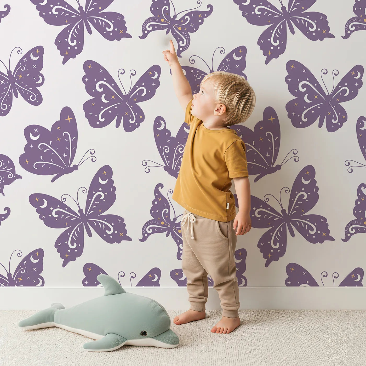 Lovely child standing in front of Whimsy Tots Celestial Wings Butterfly Wallpaper in Lilac Lavender with butterfly, moon, star, swirl in design.