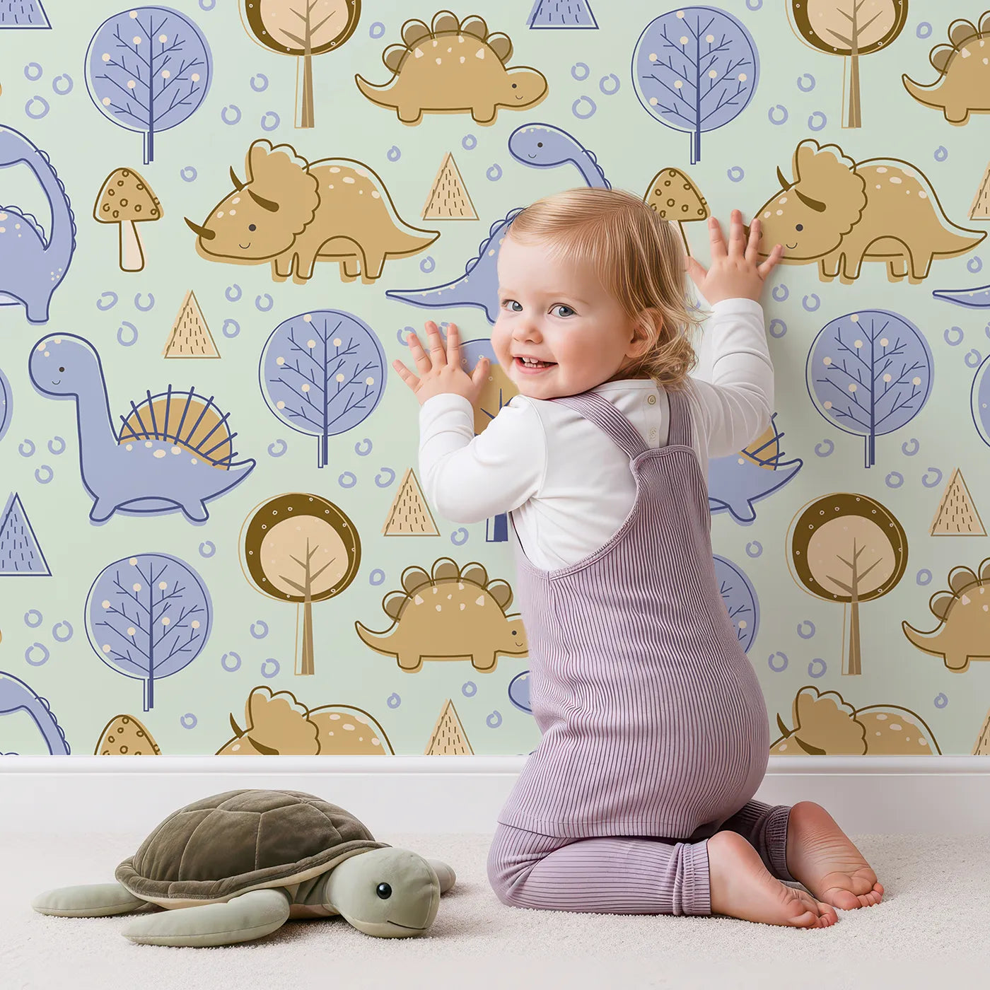 Lovely child standing in front of Whimsy Tots Jurassic Forest Friends Wallpaper in Mint Green with dinosaur, tree, triangle, dino, forest in design.
