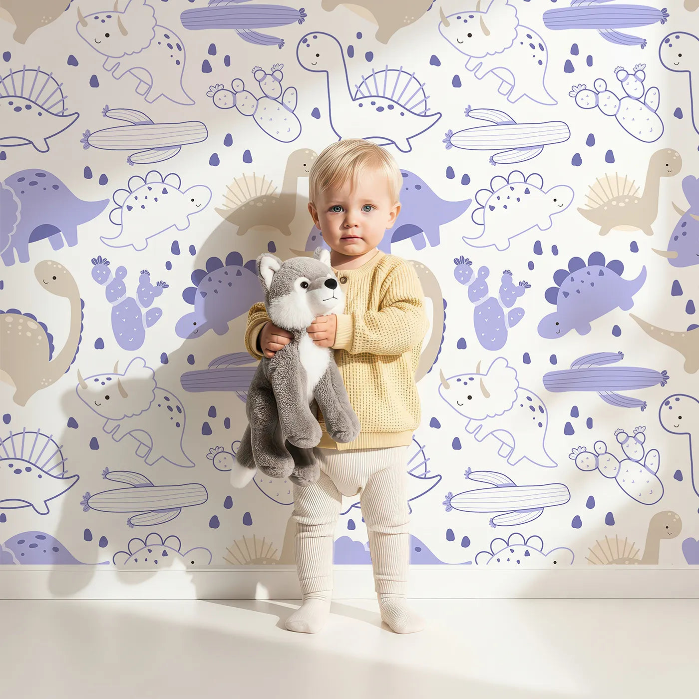 Lovely child standing in front of Whimsy Tots Cactus Canyon Dinos Wallpaper in Lilac Lavender with dinosaur, cactus, rock, spike in design.