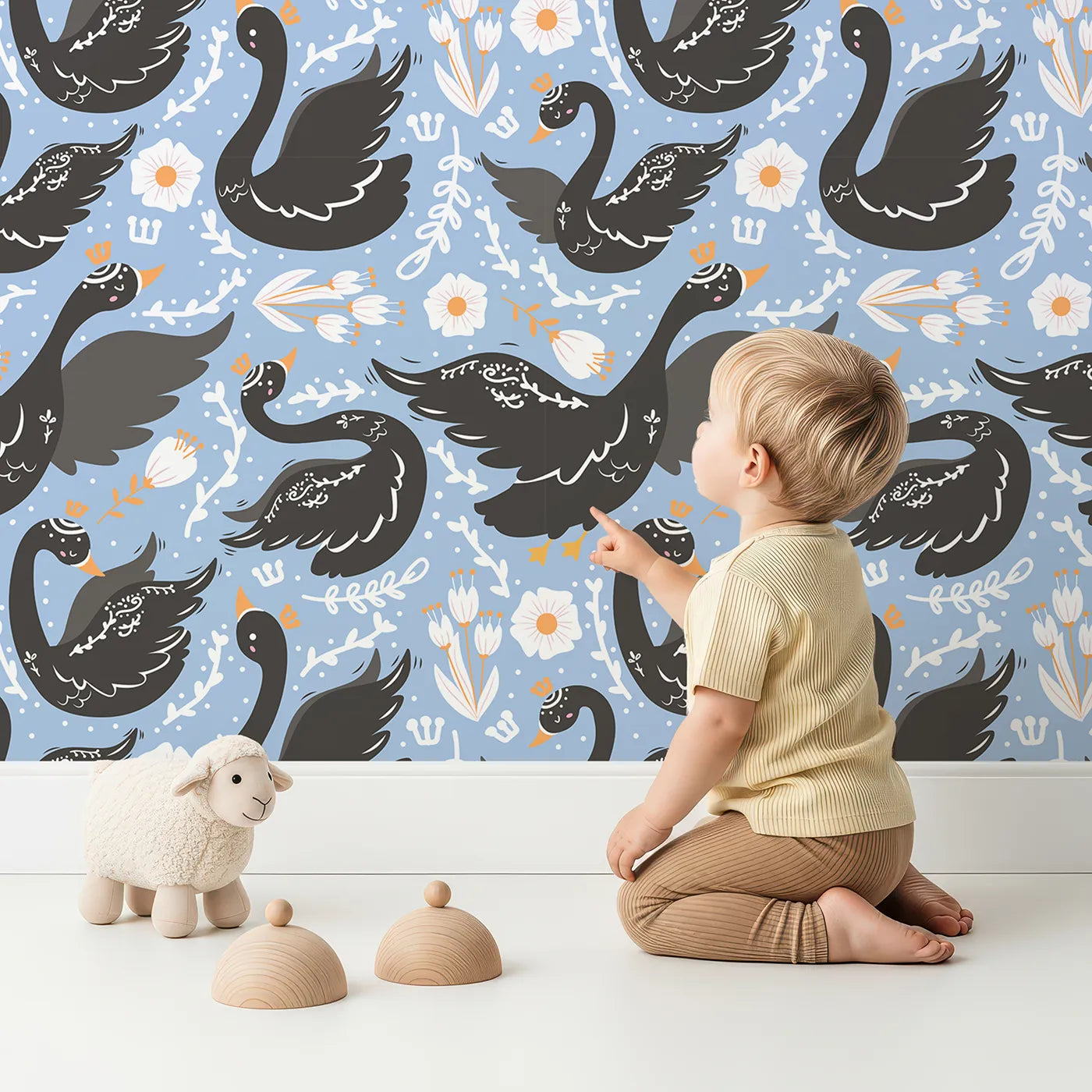 Lovely child standing in front of Whimsy Tots Regal Swan Parade Wallpaper in Sky Blue with swan, flower, crown, tulip, leaf in design.