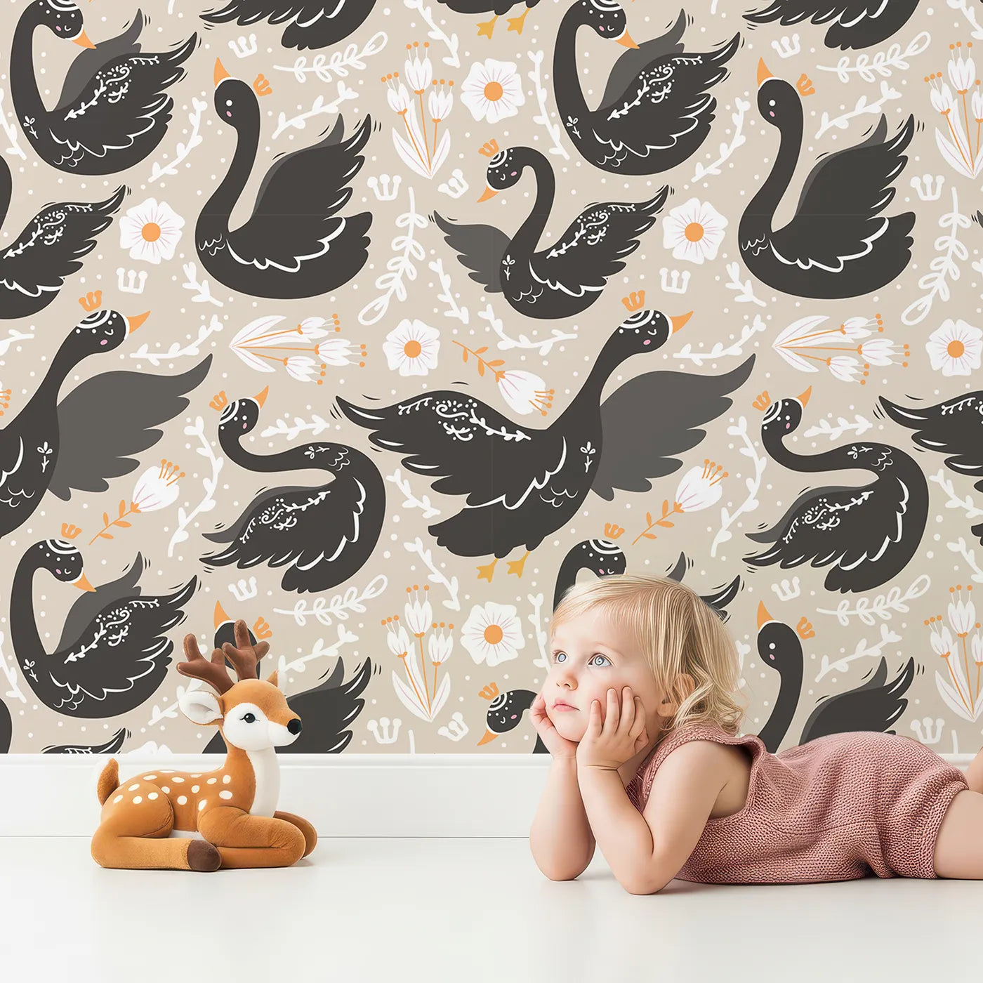 Lovely child standing in front of Whimsy Tots Regal Swan Parade Wallpaper in Beige with swan, flower, crown, leaf in design.