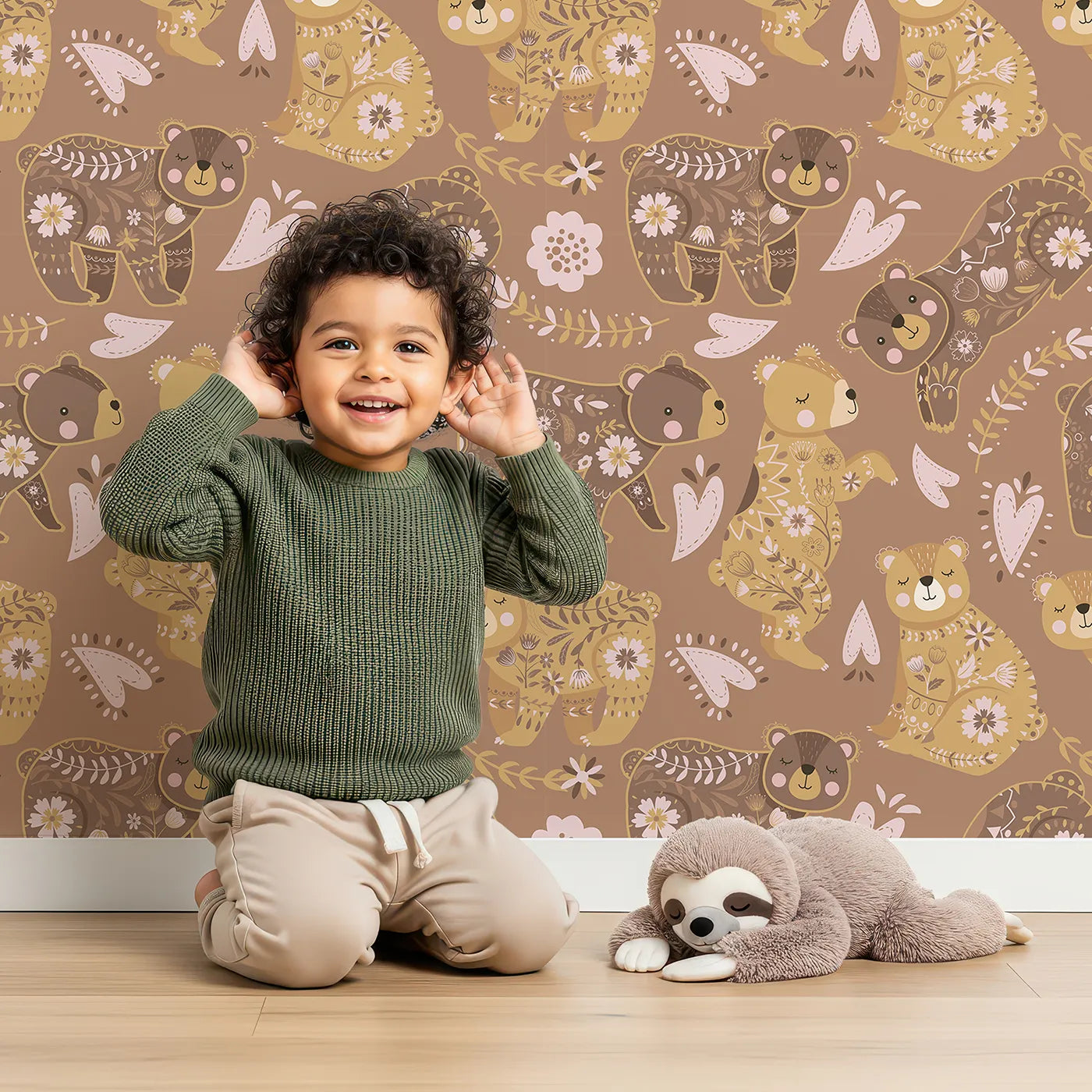 Lovely child standing in front of Whimsy Tots Floral Snuggle Bears Wallpaper in Mocha Brown with bear, flower, heart, leaf in design.