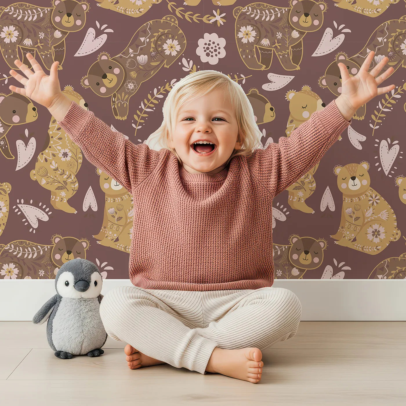 Lovely child standing in front of Whimsy Tots Floral Snuggle Bears Wallpaper in Berry Plum with bear, flower, heart, leaf in design.