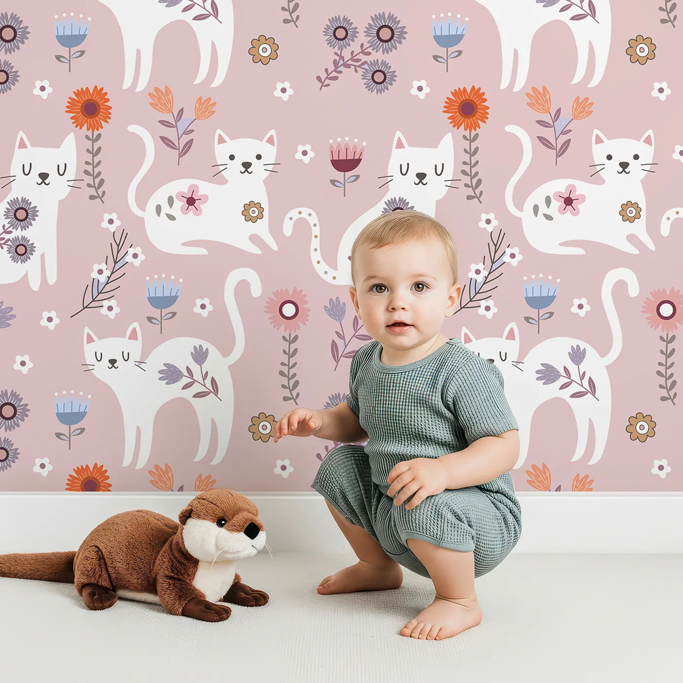 Lovely child standing in front of Whimsy Tots Floral Kitty Parade Wallpaper in Dusty Rose Pink with cat, flower, kitten, daisy in design.