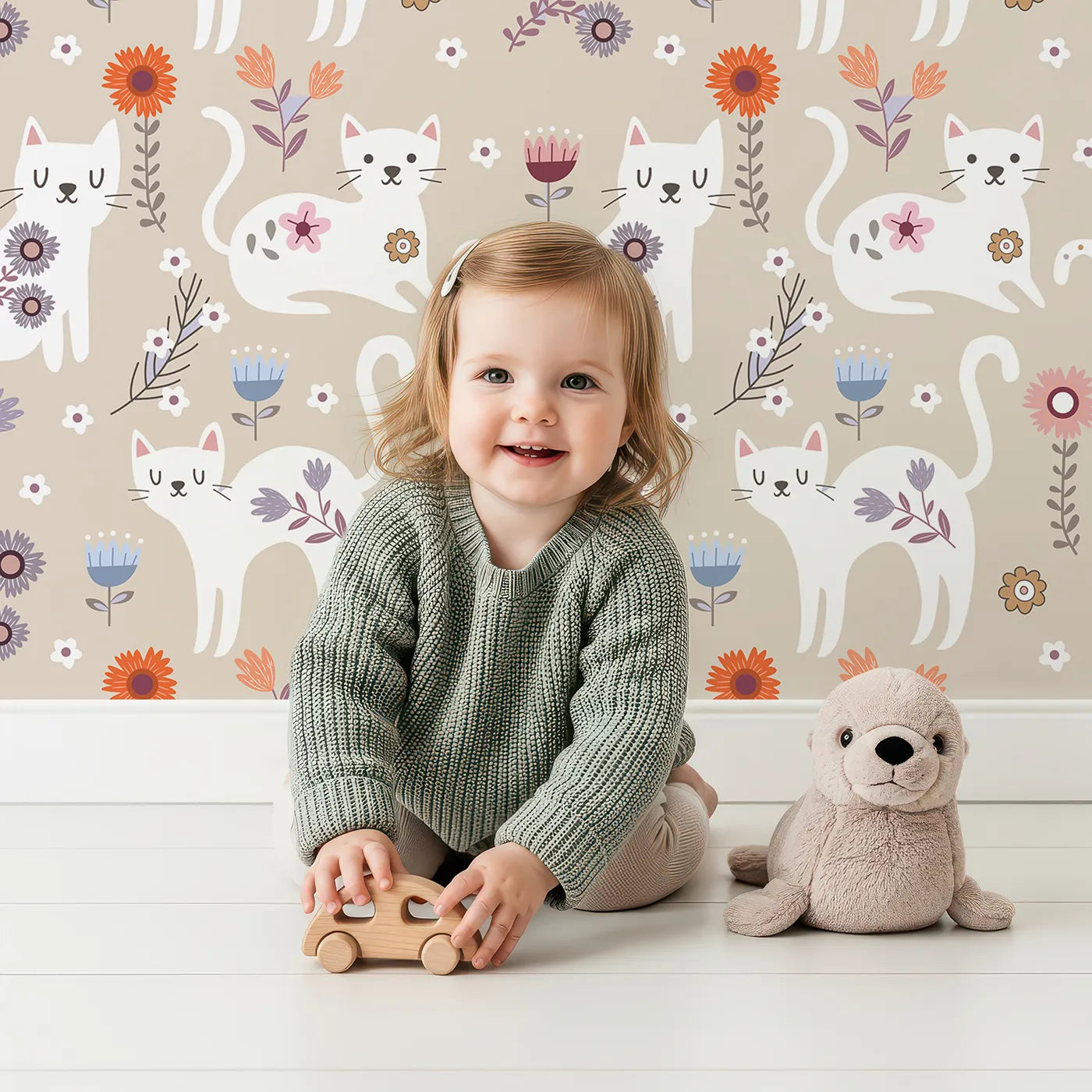 Lovely child standing in front of Whimsy Tots Floral Kitty Parade Wallpaper in Oat Beige with cat, flower, kitten, daisy in design.