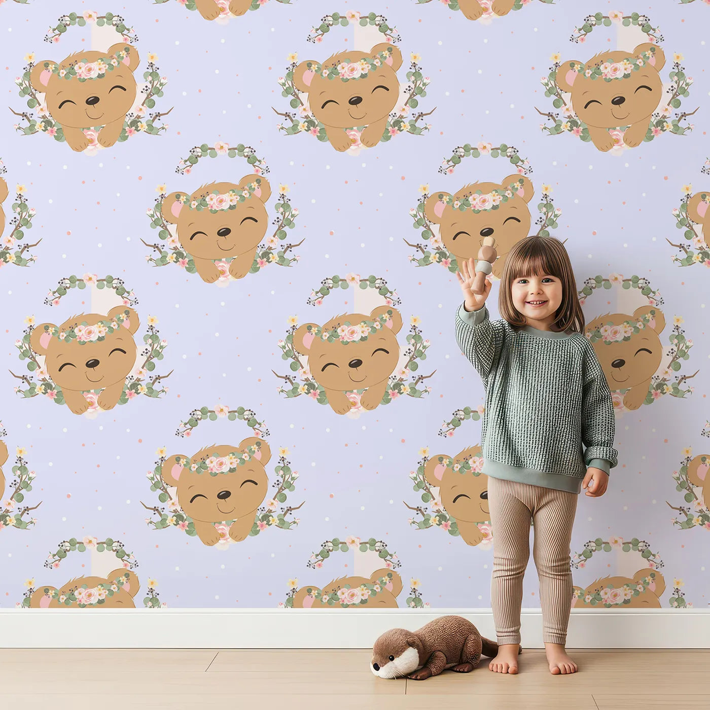 Lovely child standing in front of Whimsy Tots Floral Bear Hugs Wallpaper in Lavender Mist with bear, flower, crown, branch, leaf in design.