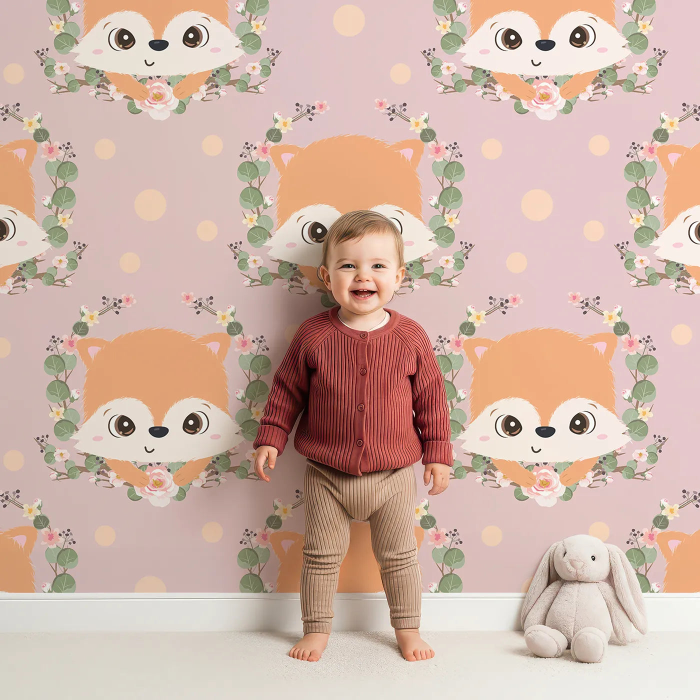 Lovely child standing in front of Whimsy Tots Floral Fox Peek Wallpaper in Rosewood Blush Pink with fox, flower, crown, leaf, polka in design.