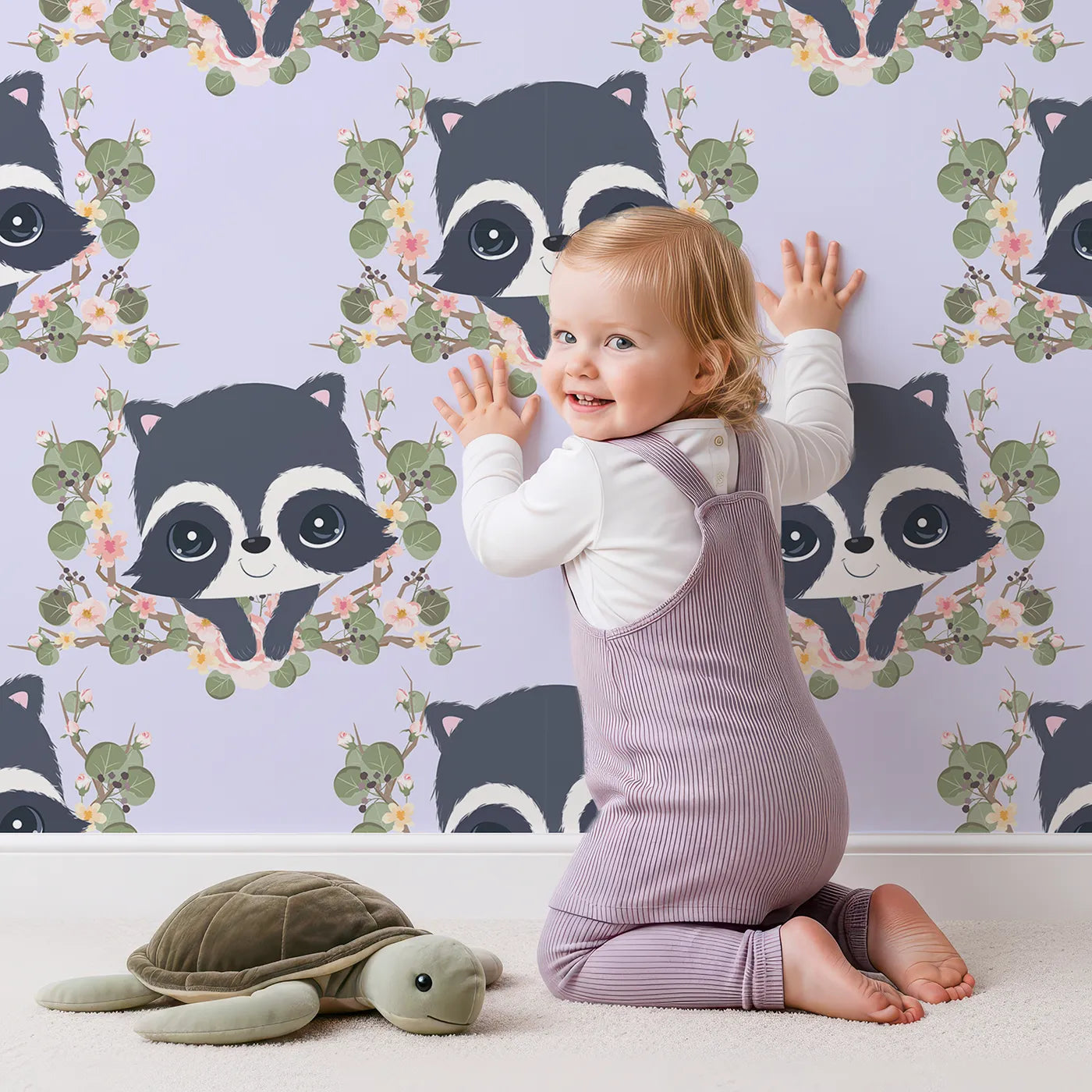 Lovely child standing in front of Whimsy Tots Floral Raccoon Peek Wallpaper in Lavender Mist with raccoon, flower, crown, branch, leaf in design.
