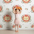 Lovely child standing in front of Whimsy Tots Little Lion Blossom Parade Wallpaper in Soft White with lion, flower, wreath, leaf, blossom in design.