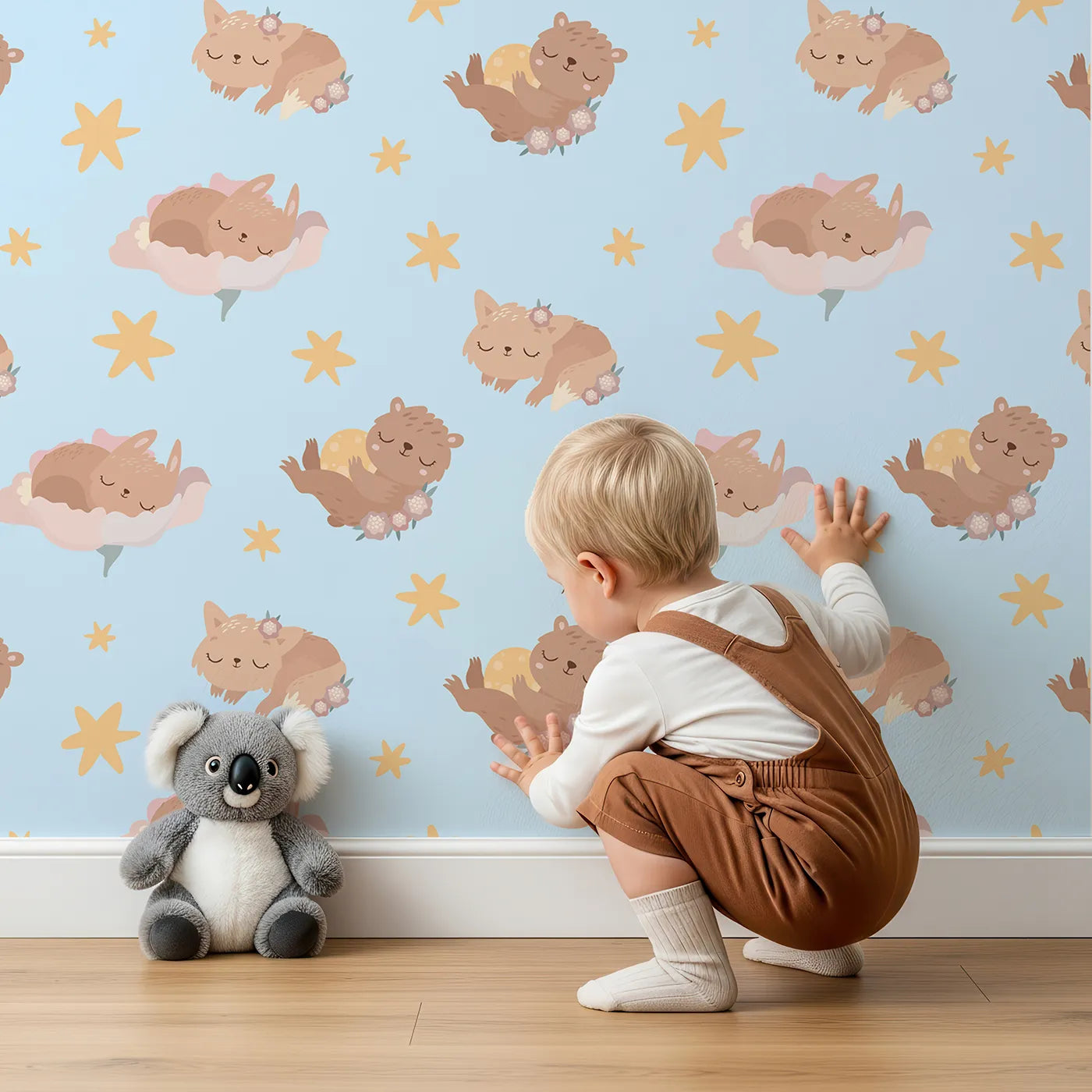 Lovely child standing in front of Whimsy Tots Woodland Nap Parade Wallpaper in Dreamy Blue with bear, bunny, fox, flower, star in design.