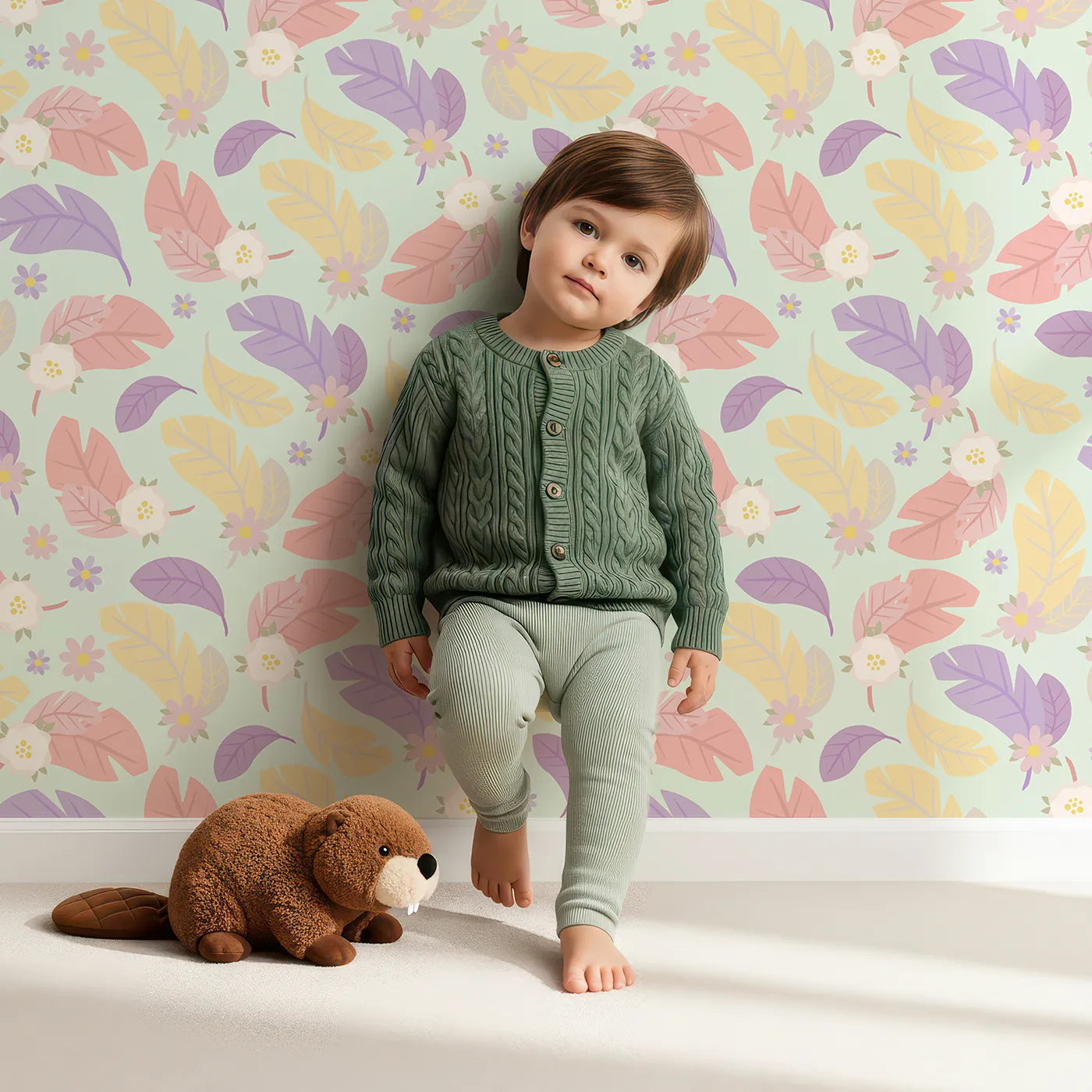 Lovely child standing in front of Whimsy Tots Pastel Feather Garden Wallpaper in Mint Whisper Green with flower, leaf, feather, petal in design.