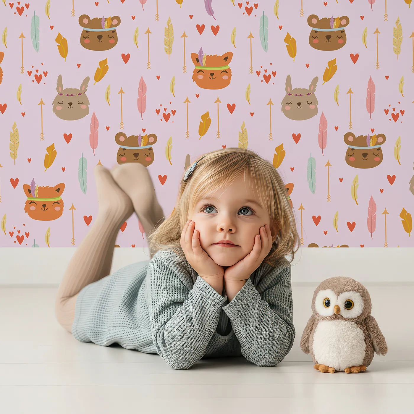 Lovely child standing in front of Whimsy Tots Woodland Tribe Hearts Wallpaper in Blush Lilac Pink with bear, fox, rabbit, feather, arrow, heart in design.