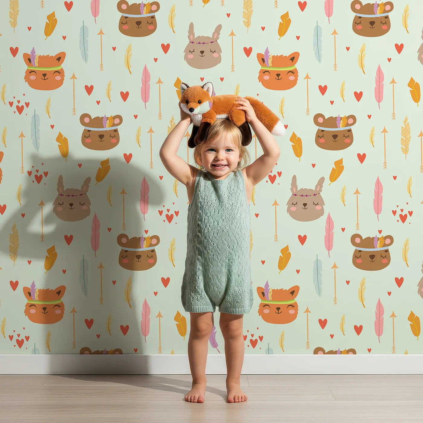 Lovely child standing in front of Whimsy Tots Woodland Tribe Hearts Wallpaper in Soft Mint Green with bear, fox, rabbit, feather, arrow, heart in design.