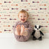 Lovely child standing in front of Whimsy Tots Boho Arrow Trail Wallpaper in Oat Beige with arrow, diamond in design.