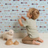 Lovely child standing in front of Whimsy Tots Boho Arrow Trail Wallpaper in Soft Sky with arrow, diamond in design.