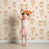 Lovely child standing in front of Whimsy Tots Heartful Bunny Parade Wallpaper in Cream with rabbit, heart in design.
