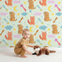 Lovely child standing in front of Whimsy Tots Arrow Pup and Foxy Night Parade Wallpaper in Mint Green with dog, fox, moon, arrow, star, cloud in design.